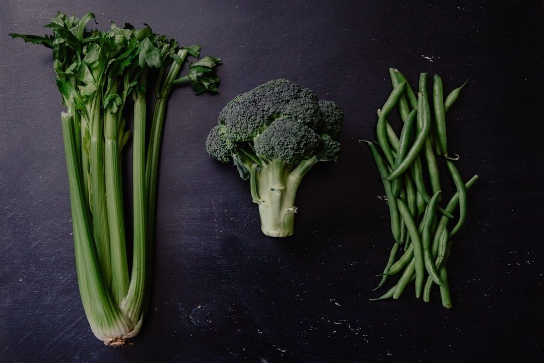 Selleri, broccoli och gröna bönor på en mörk yta